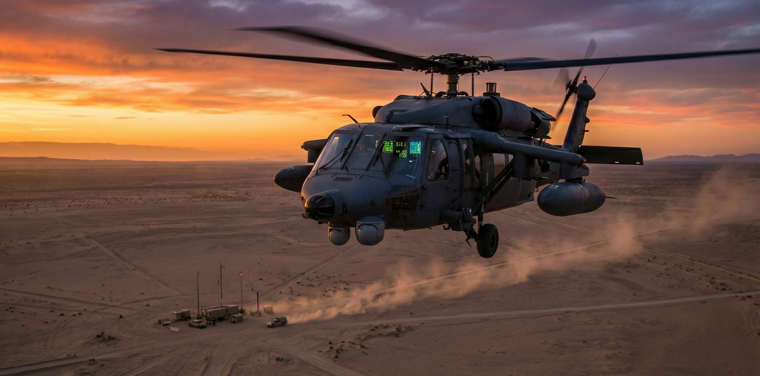 Military helicopter equipped with autonomous flight systems flying over a desert test range at dusk with electronic sensor arrays visible