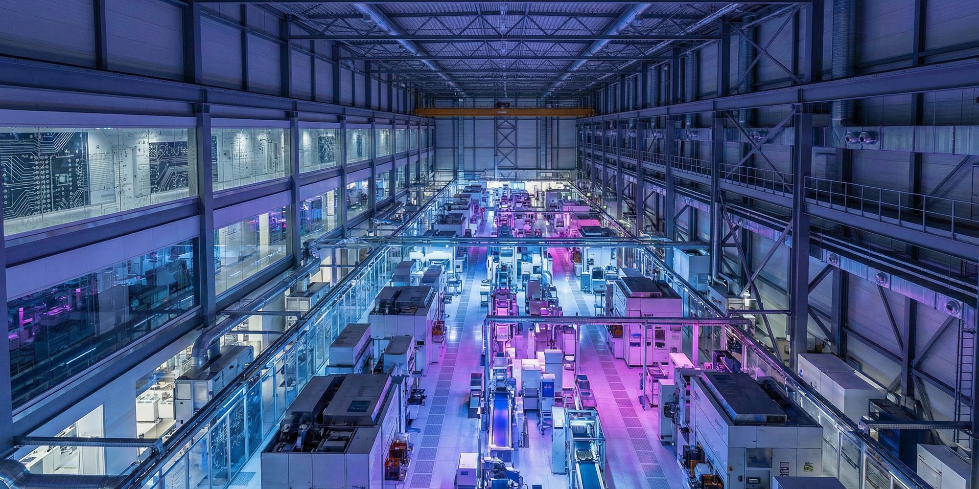 Interior of an advanced semiconductor fabrication facility with rows of cleanroom manufacturing equipment illuminated in blue and purple light
