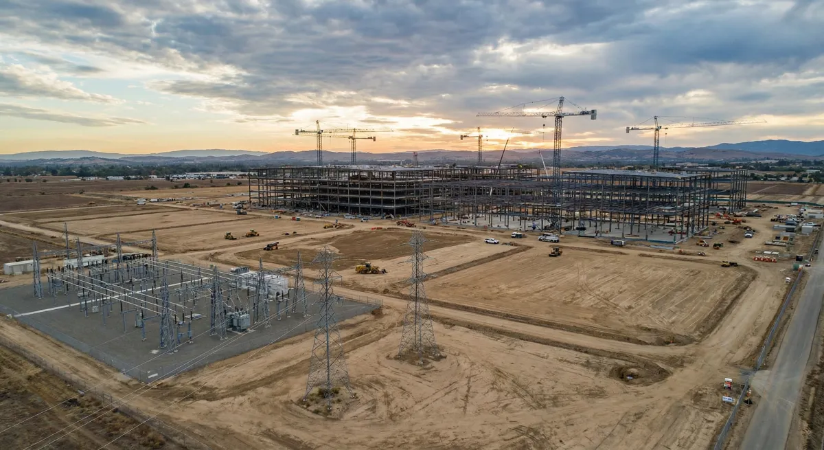 Data center construction site with cranes and power infrastructure in suburban setting
