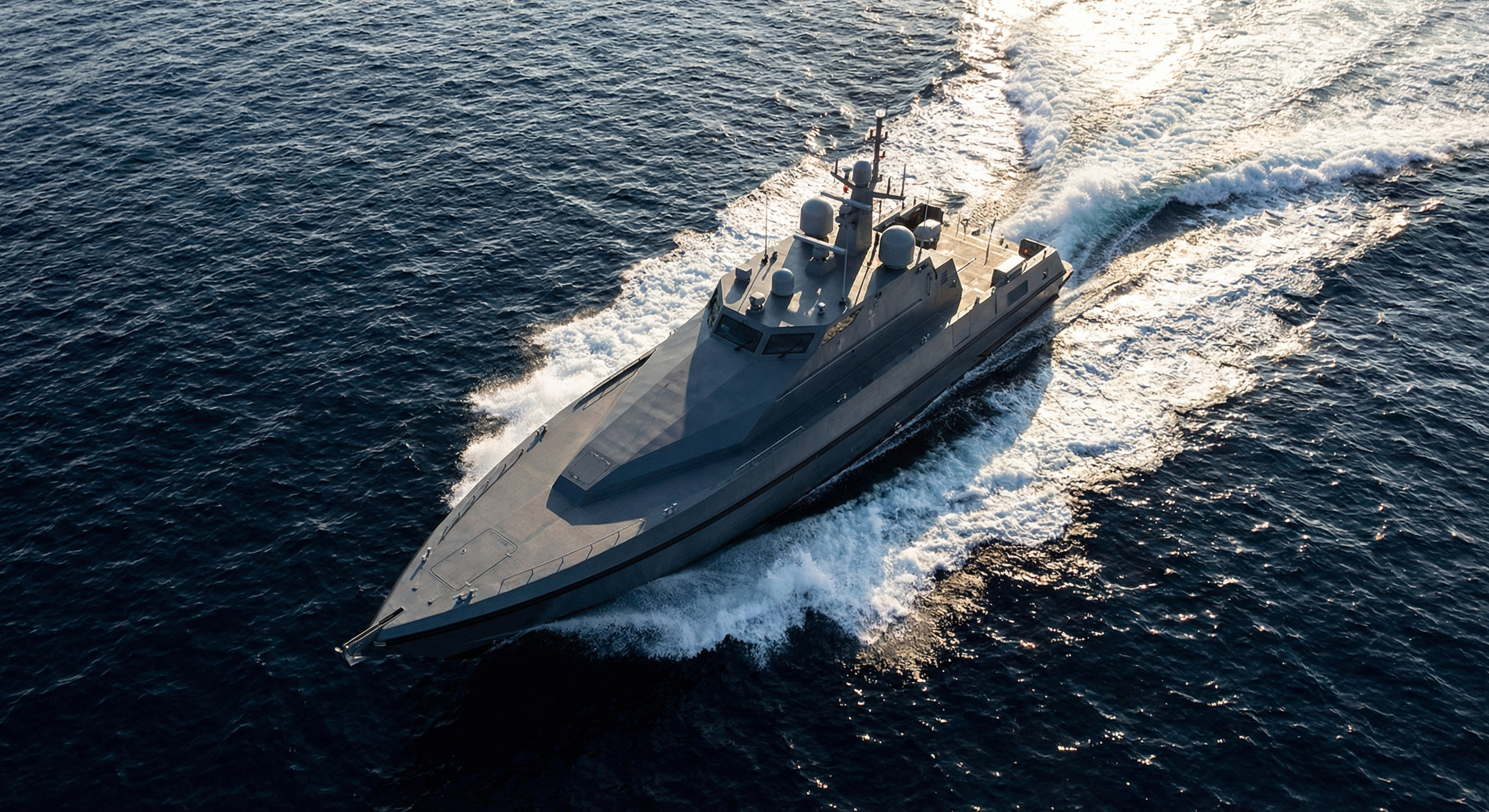 Sleek angular autonomous unmanned surface vessel cutting through dark ocean waters at high speed with sensor array mounted on deck